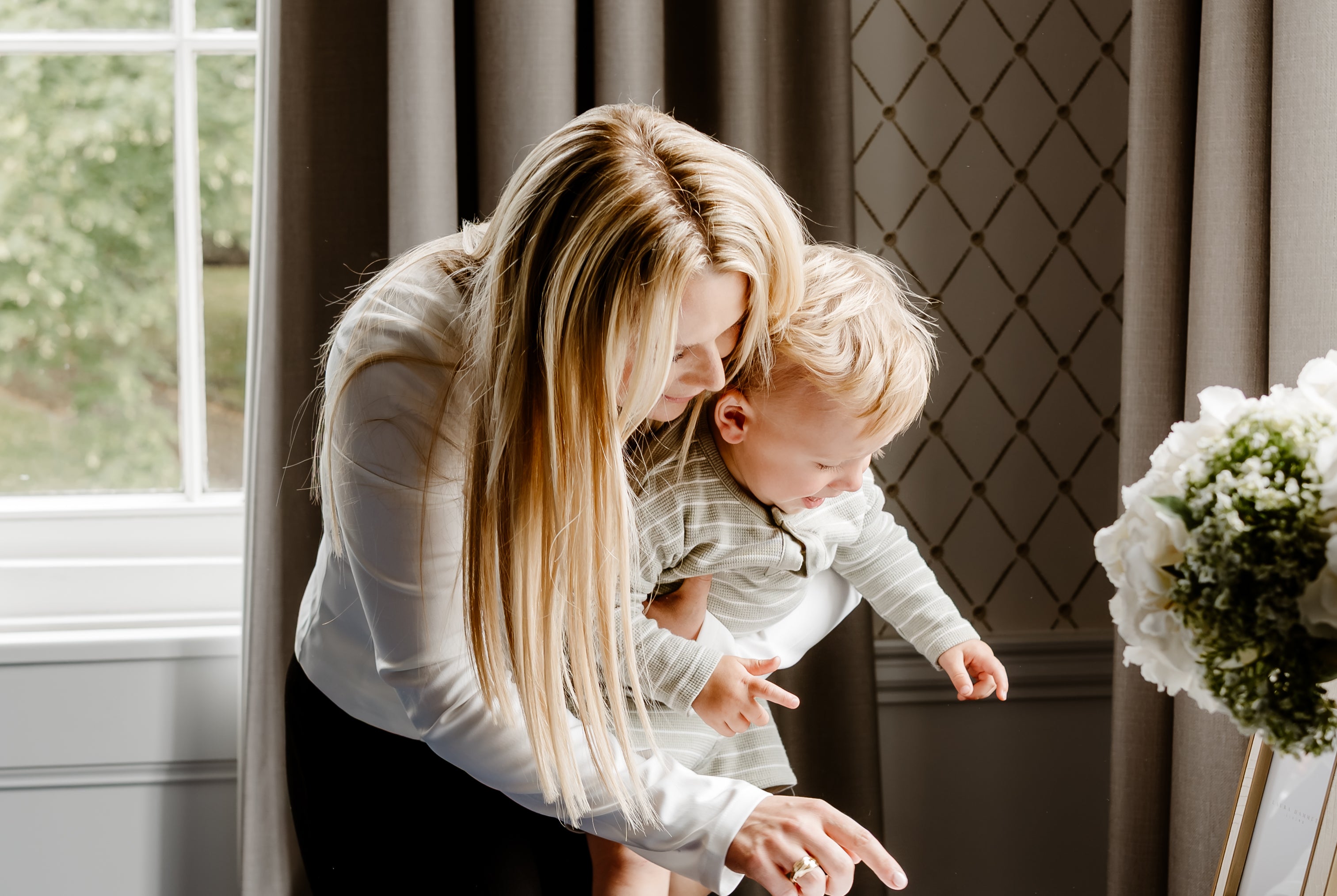 Woman and child at a desk with a window and decorative elements in the background