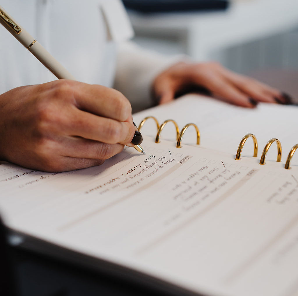 Person writing in a notebook with a pen on a blurred background