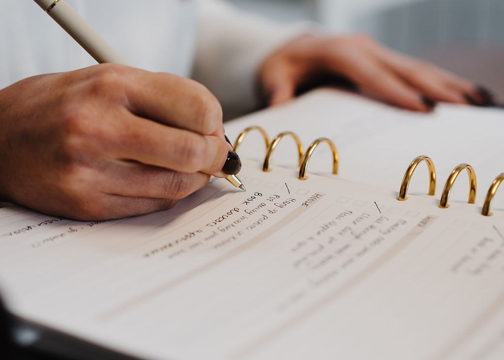 Person writing in a notebook with a pen on a blurred background