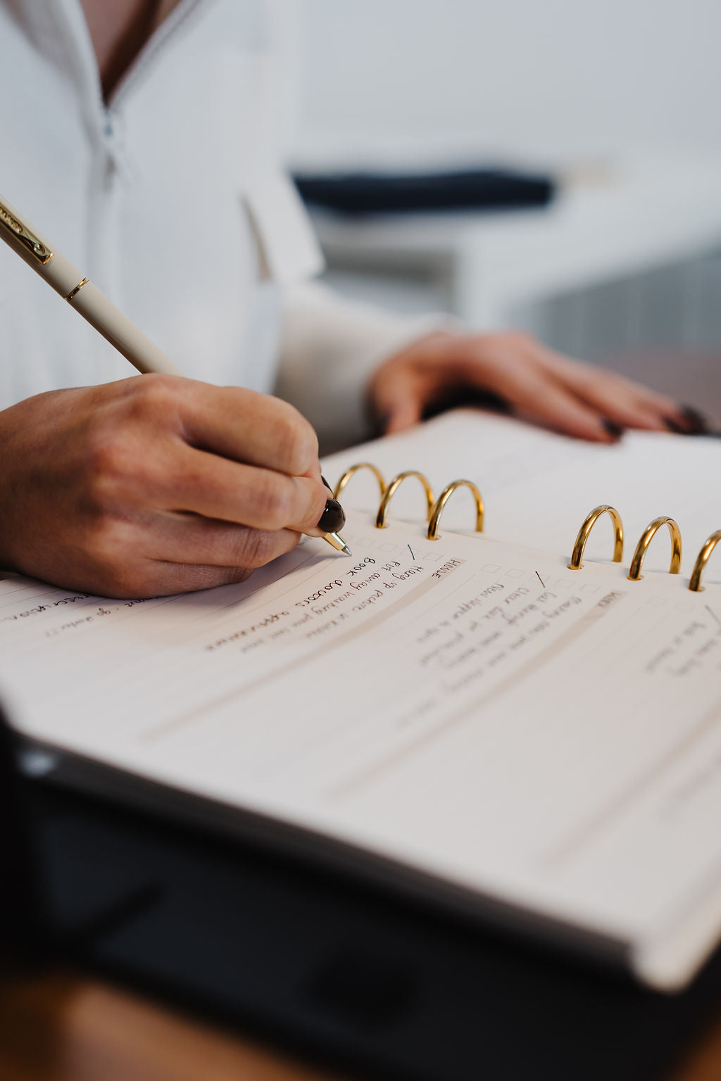 Person writing in a notebook with a pen on a blurred background