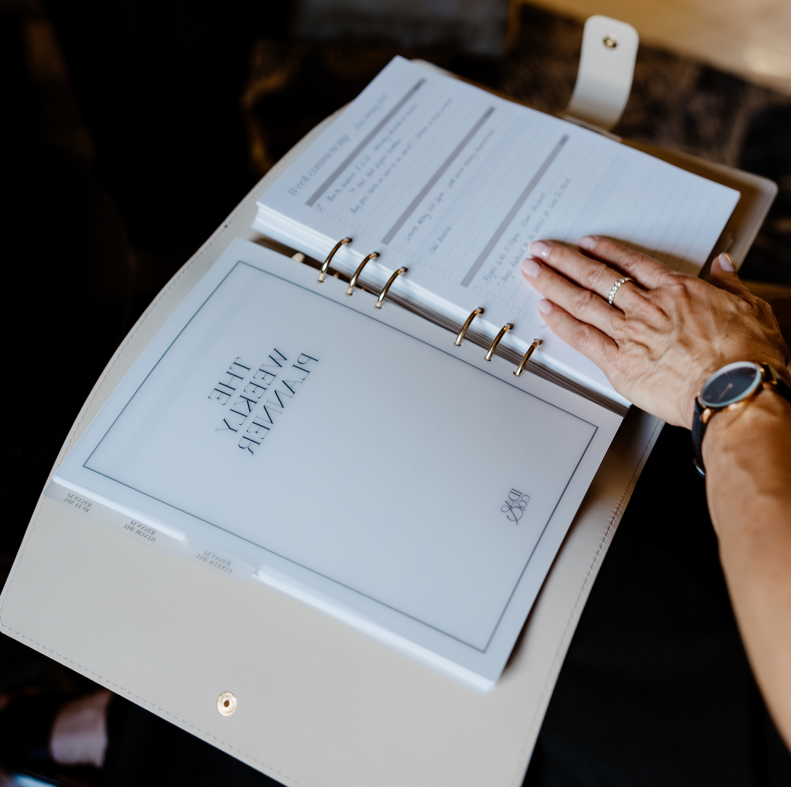 Person holding a planner with visible text and a hand on the cover