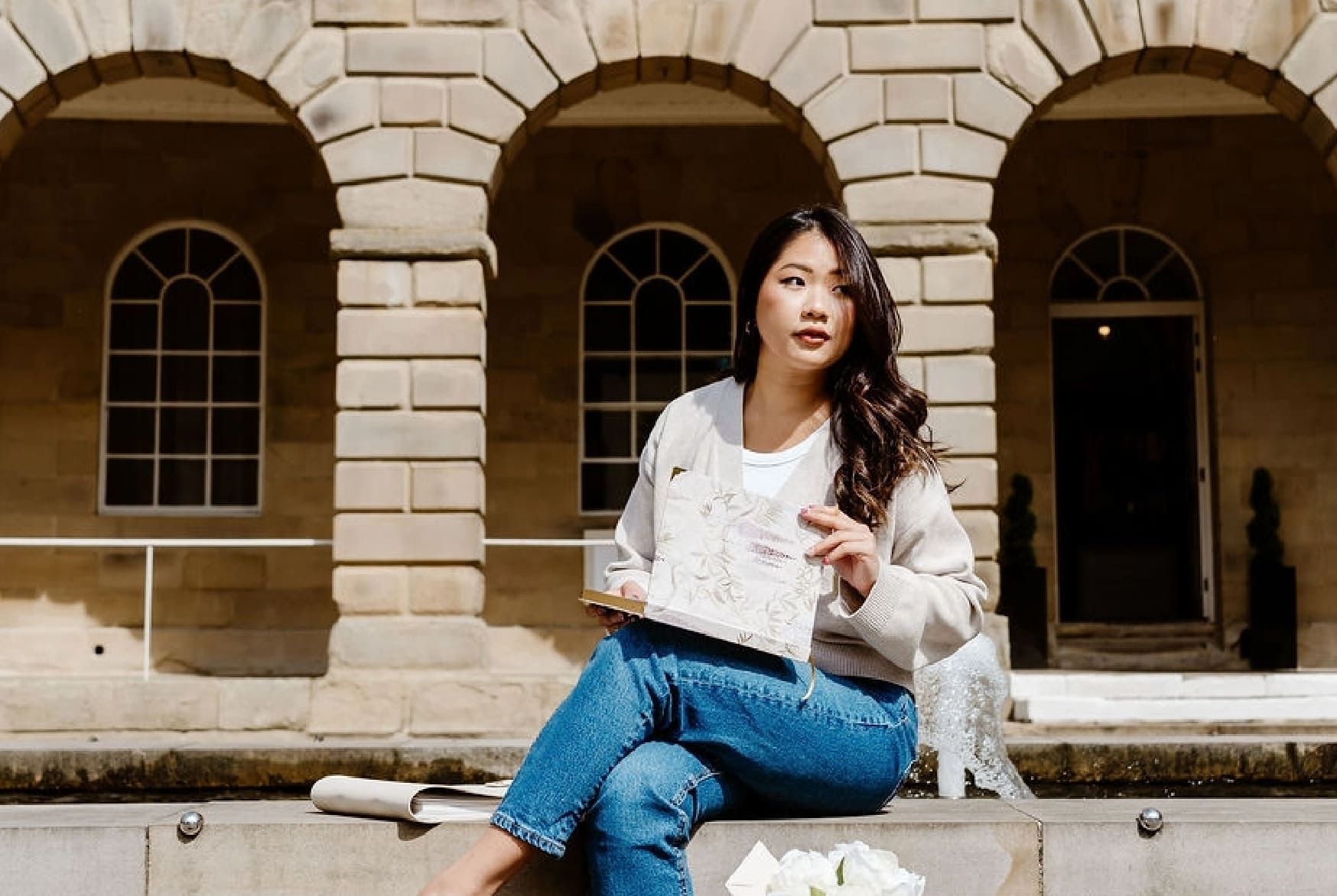 Woman sitting on steps in front of a stone building with arched windows