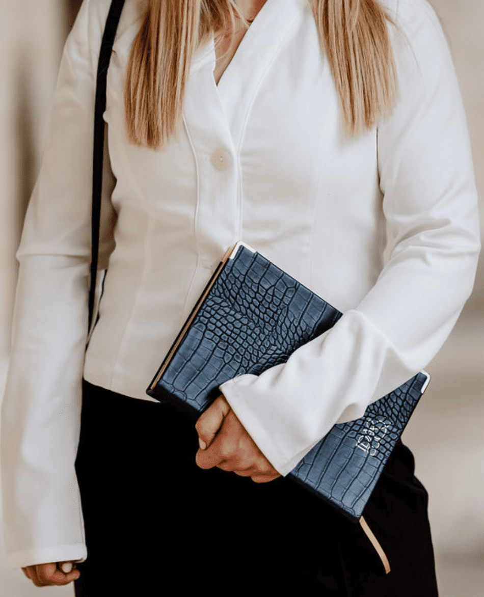 Person holding a black crocodile-patterned planner