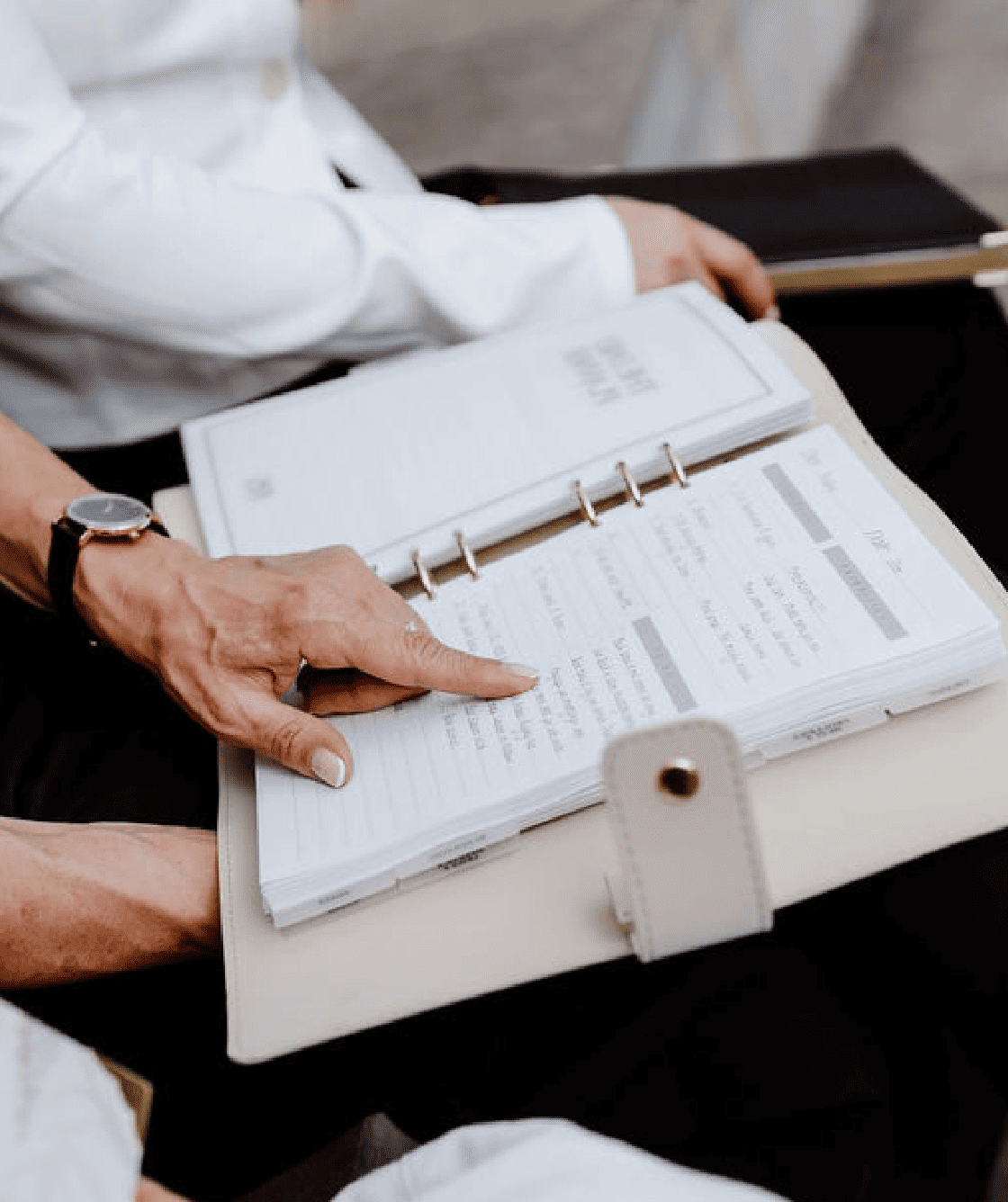 Person holding an open planner with a pen on a table