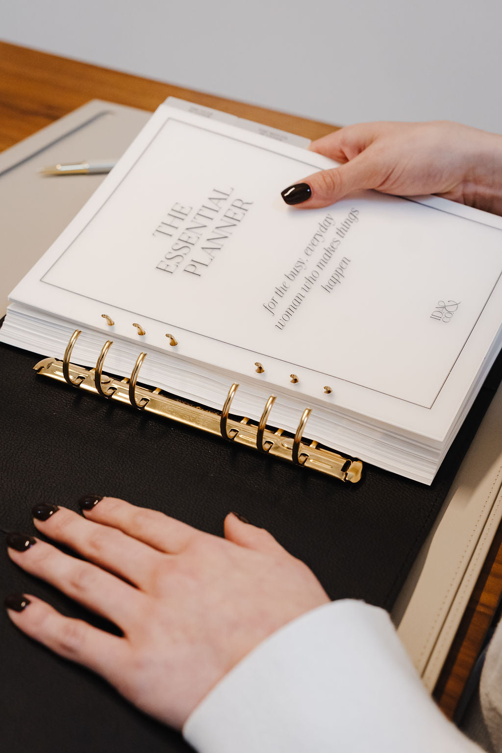Person holding 'The Essential Planner' on a wooden surface