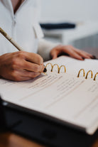 Person writing in a notebook with a pen on a blurred background