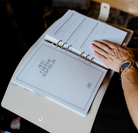 Person holding a planner with visible text and a hand on the cover