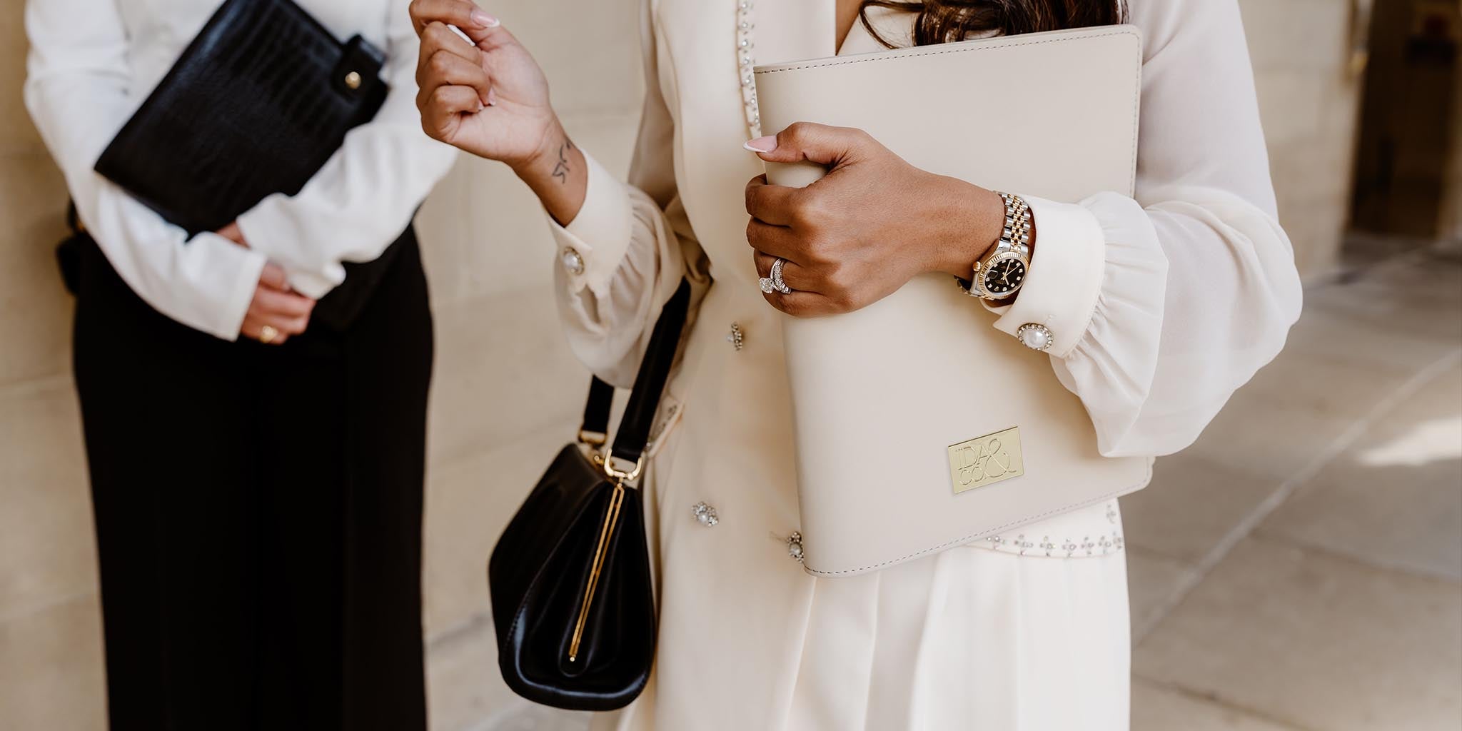 Two people holding planners, one black and one beige.